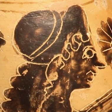 Detail of the alabastron: the head in profile facing right, wearing a close-fitting cap, painted in black silhouette with incised contours on the pale ground.